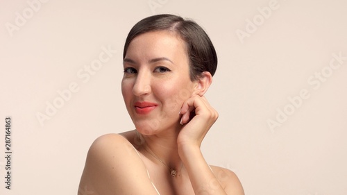 beauty brunette with short haircut model in studio alone with ideal shiny skin smiling to camera