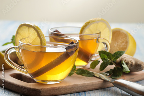 Tea with lemon and a cinnamon stick with ginger and mint in glass cups on a brown wooden table. a warming drink. Autumn or winter drink.