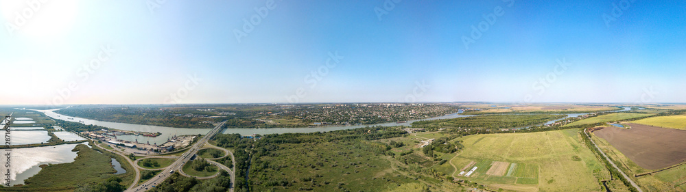Aerial view (drone view) on a sunny summer day over the Don River at the intersection with the M4-Don motorway. Road junction, bridge and port. The high right bank and the city of Aksai on its hills