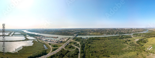 Aerial view (drone view) on a sunny summer day over the Don River at the intersection with the M4-Don motorway. Road junction, bridge and port. The high right bank and the city of Aksai on its hills