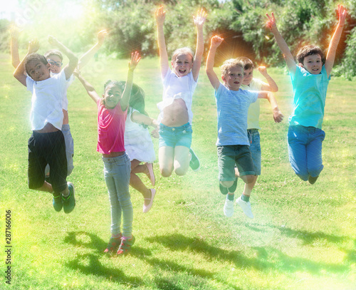Happy team of friends children jumping together in park