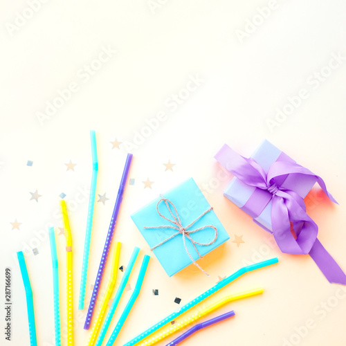 Gift box on a yellow background, festive decorations drinking straws and confetti. Holiday concept. Fat lay.