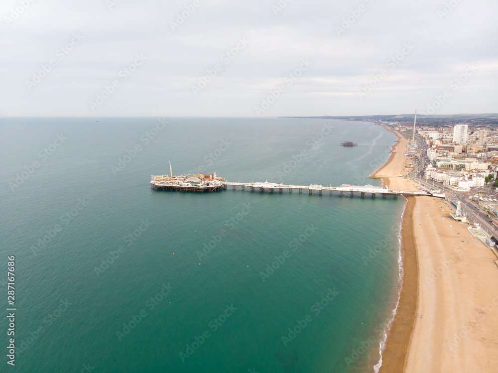 Aerial photo of the famous Brighton Pier and ocean located in the south coast of England UK that is part of the City of Brighton and Hove, taken on a bright sunny day showing the fairground rides.