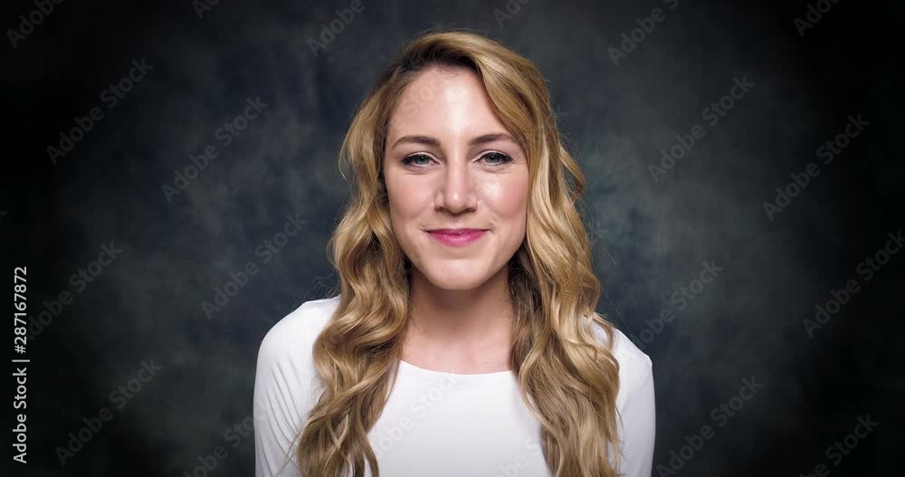 Beautiful Blonde Woman Smiling at the Camera With Blue Eyes on a dark background. 4K video. Beautiful Blonde Woman Smiling at the Camera With Blue Eyes on a dark background. 4K video.
