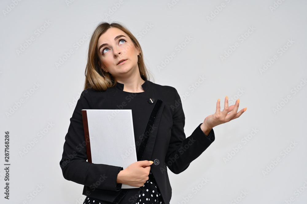 Portrait of a cute middle-aged brunette woman with beautiful curly hair and perfect face skin in a black business suit with a folder in her hands on a white background. Beauty, brightness, smile. Portrait of a cute middle-aged brunette woman with beautiful curly hair and perfect face skin in a black business suit with a folder in her hands on a white background. Beauty, brightness, smile.