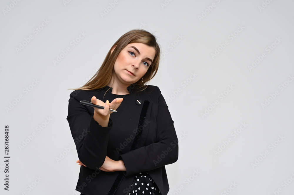 Portrait of a cute middle-aged brunette woman with beautiful curly hair and perfect face skin in a black business suit with a pen in her hands on a white background. Beauty, brightness, smile. Portrait of a cute middle-aged brunette woman with beautiful curly hair and perfect face skin in a black business suit with a pen in her hands on a white background. Beauty, brightness, smile.