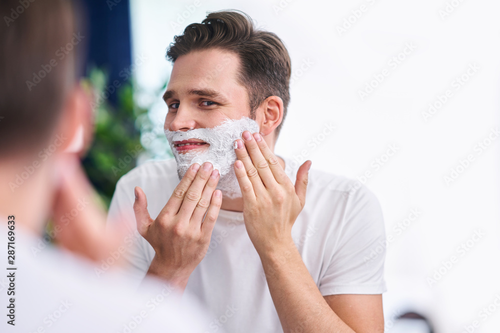Portrait of adult man shaving in the bathroom