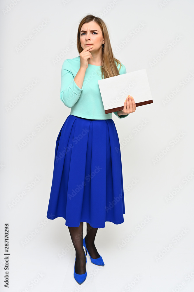 Full-length Vertical Portrait of a cute brunette middle-aged manager woman with beautiful curly hair in a business suit and blue skirt on a white background with a folder in her hands. Full-length Vertical Portrait of a cute brunette middle-aged manager woman with beautiful curly hair in a business suit and blue skirt on a white background with a folder in her hands.