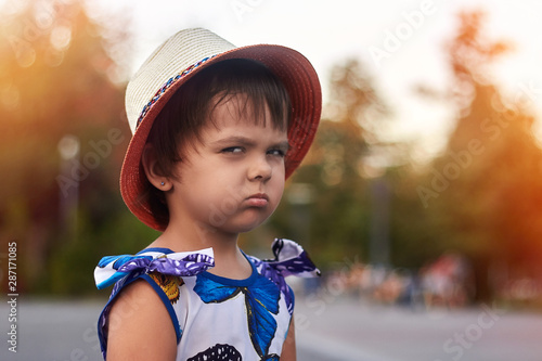 Portrait of a young girl in hat looking contemptuously and appreciatively. Concept emotion appreciation and contempt