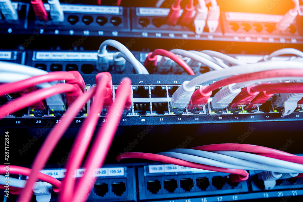 Network switch and ethernet cables in red and white colors. Data Center