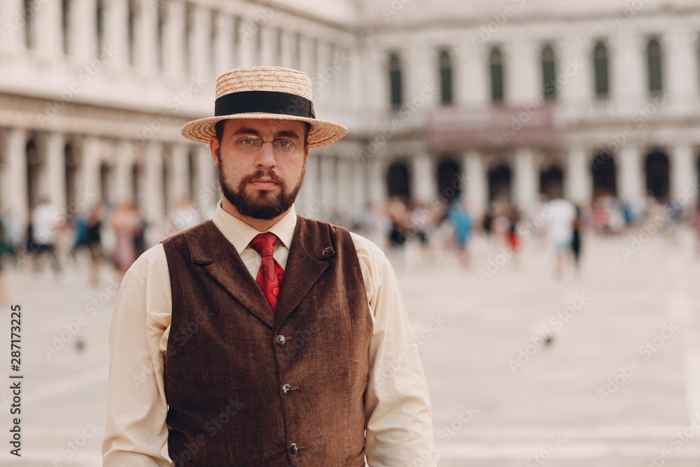 Young man in vintage suit stand on Piazza San Marco Square in Venice, Italy