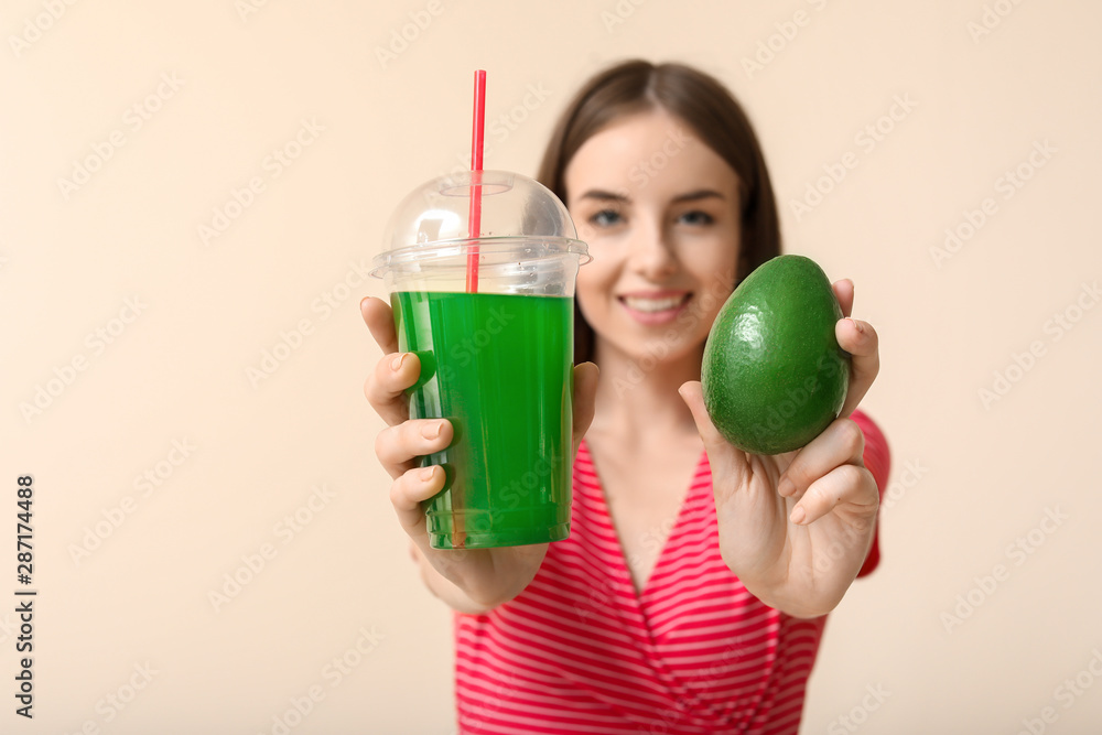 Young woman with healthy vegetable juice and avocado on light background Young woman with healthy vegetable juice and avocado on light background