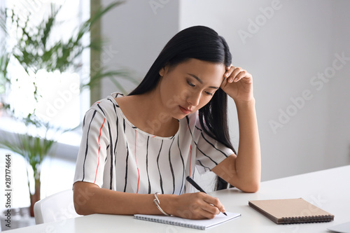 Thoughtful young woman writ...