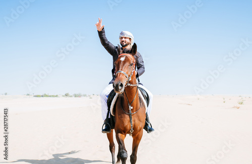 Arabian man with traditional clothes riding his horse