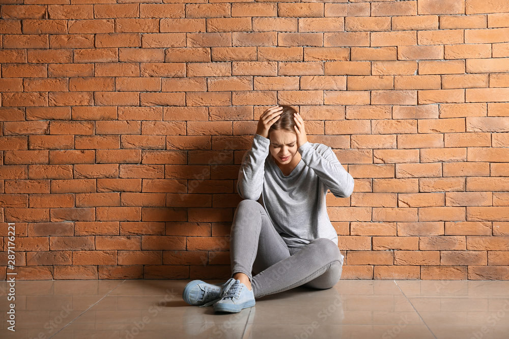 Woman having panic attack while sitting near brick wall Woman having panic attack while sitting near brick wall