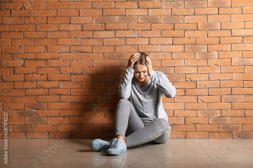 Woman having panic attack while sitting near brick wall © Pixel-Shot