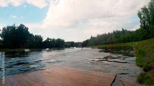 A young athlete jumps on a wakeboard in the water. Lake on a sunny day. Sport