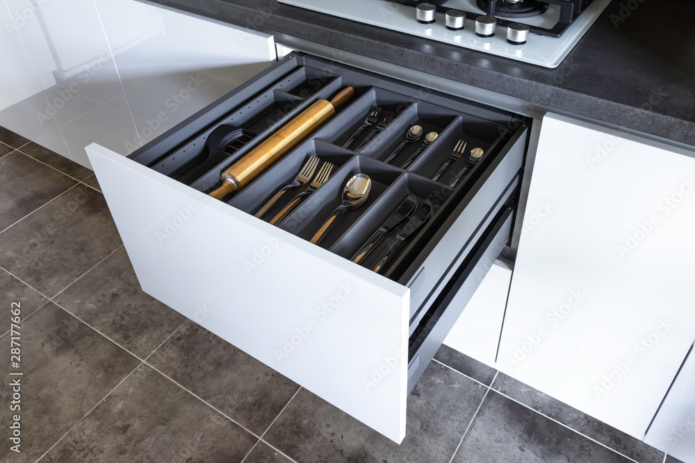 Opened drawer with cutlery inside, contemporary white grey kitchen in minimal loft style Opened drawer with cutlery inside, contemporary white grey kitchen in minimal loft style