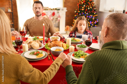 Family praying before having Christmas dinner at home © Pixel-Shot