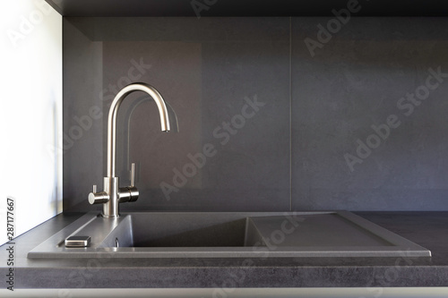 Grey granite kitchen sink with a stainless steel tap for filtered water on a grey benchtop and grey backsplash. 