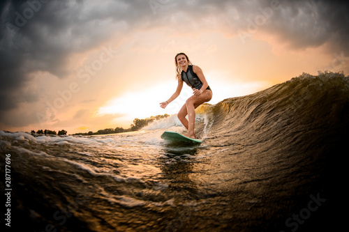 Beautiful girl riding on the wakeboard on the river on the wave photo