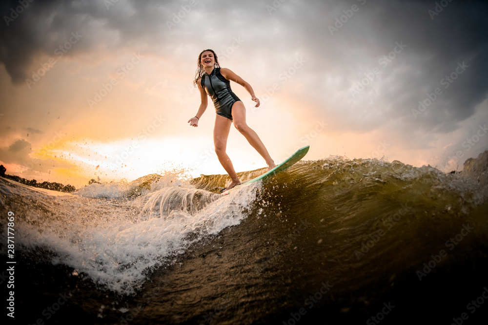 Brunette girl riding on the wakeboard on the river on the wave