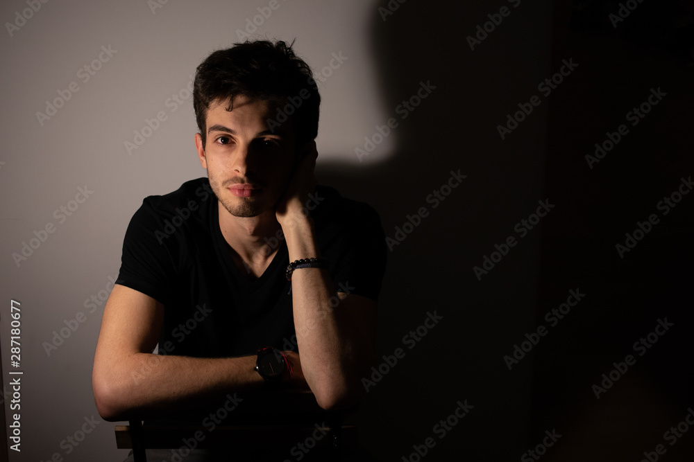 Young man teenager shadows light portrait looking forward Young man teenager shadows light portrait looking forward