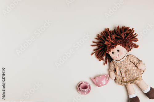 Fotografiet A doll and toy tea set on a white background