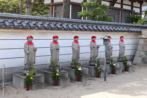 お寺の塀の前に立つ六体のお地蔵さん photo