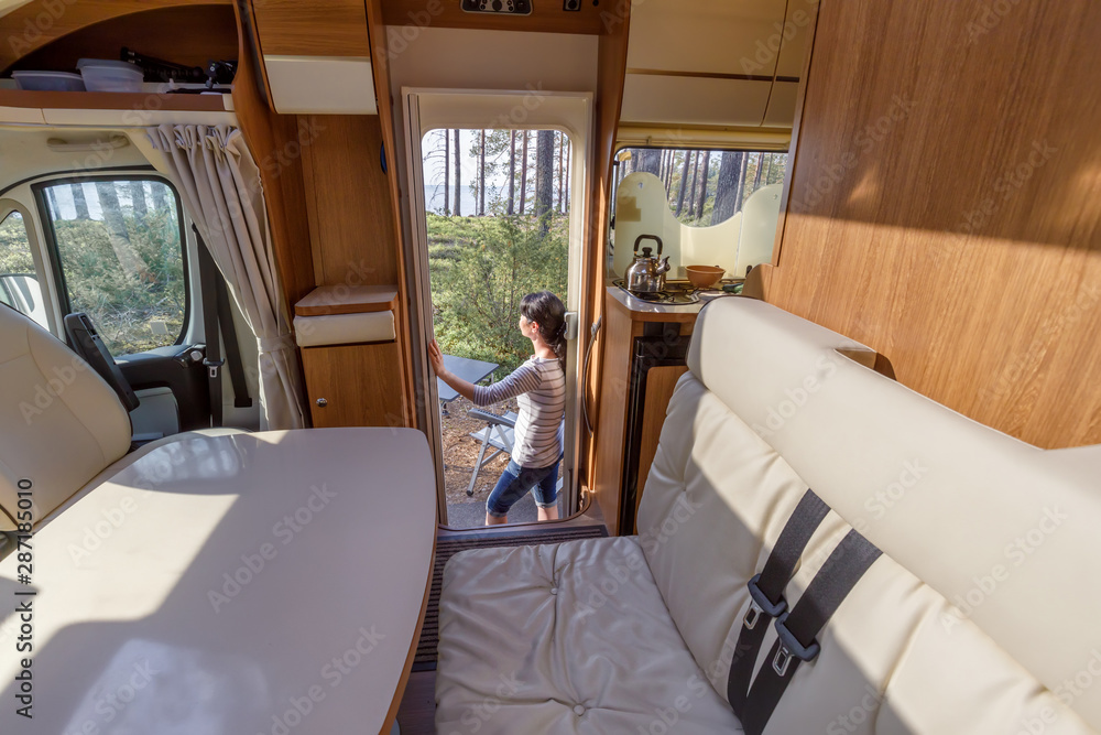 Woman in the interior of a camper RV motorhome with a cup of coffee looking at nature. - obrazy, fototapety, plakaty 