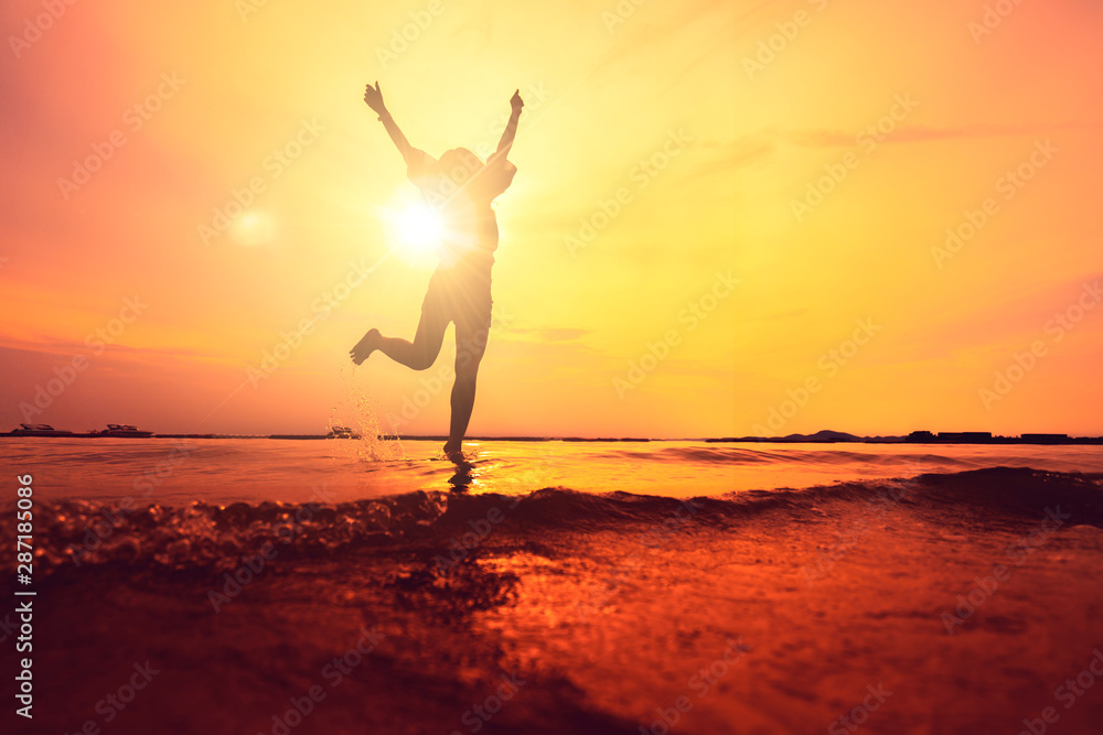 silhouette of asian teen woman jump on sunset beach freedom ideas concept