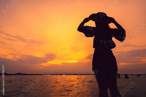 silhouette of asian teen woman hand rise hat to the sky on sunset beach freedom ideas concept