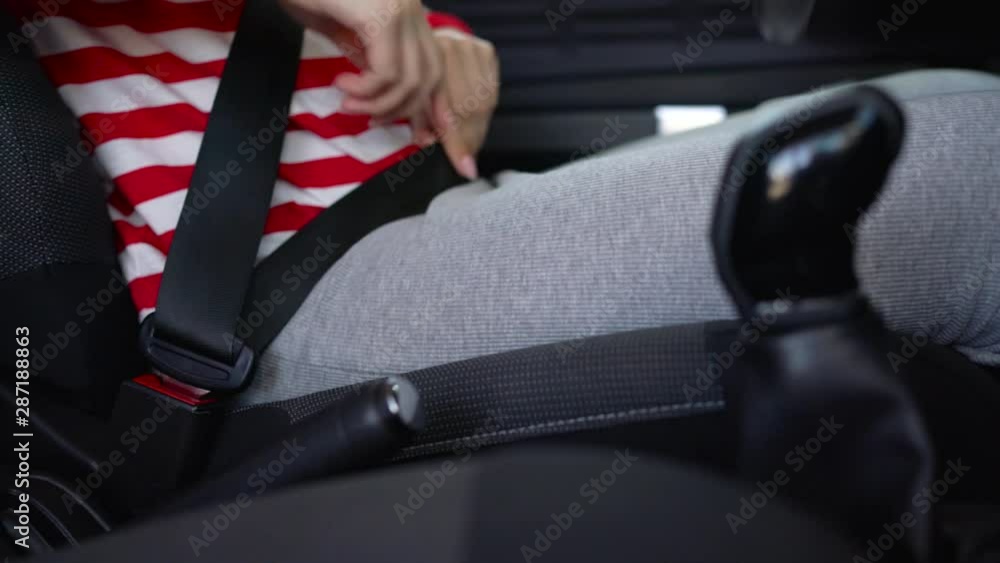 Woman fastening car safety seat belt while sitting inside of vehicle before driving Woman fastening car safety seat belt while sitting inside of vehicle before driving