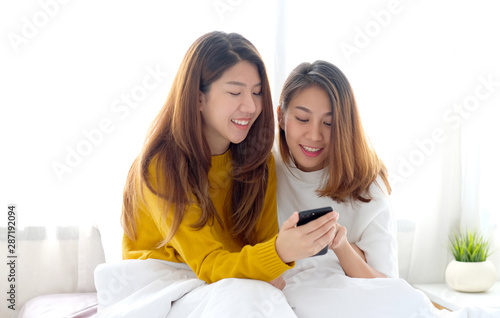 Young cute asia lesbian couple using smart phone with happiness at home, lgbt, homosexual, lesbian couple lifestyle
