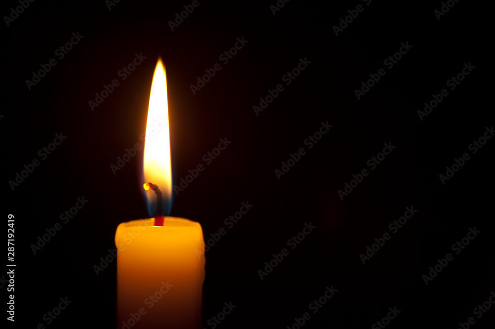 Close-up of single burning candle on black background. Copy space. Horizontal shot. Close-up of single burning candle on black background. Copy space. Horizontal shot.
