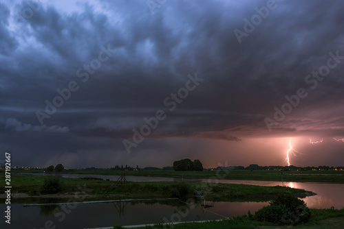 Shelfcloud and lightning from a severe thunderstorm near a river at dusk