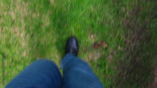 POV looking down at male legs in jeans and boots walking from pavement to grass and back - fast forward walk