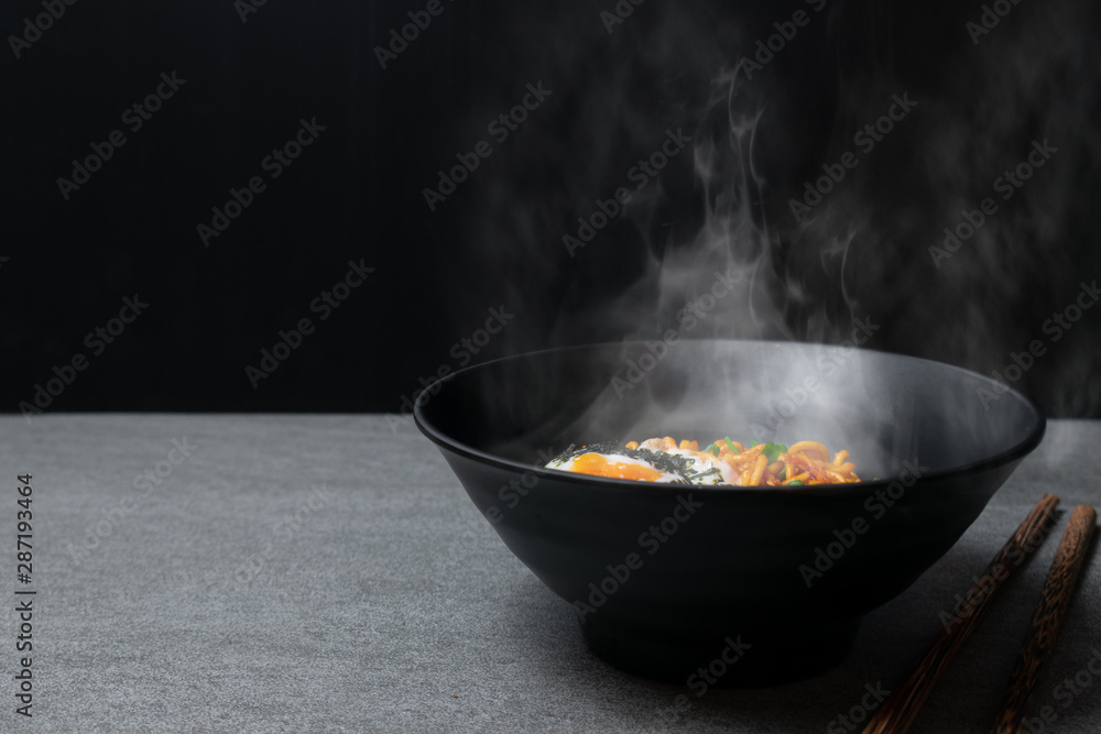 Drunken spicy noodles in black bowl with Onsen egg on the concrete table. Drunken spicy noodles in black bowl with Onsen egg on the concrete table.