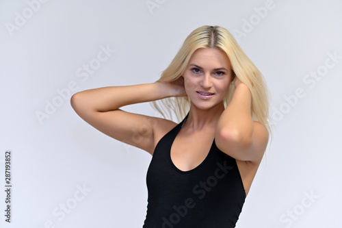 Portrait of a cute girl, a young blonde woman with beautiful curly hair in a black T-shirt on a white background. Beauty, brightness, smile, emotions.