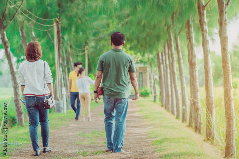 Couple walking and taking photos under the pine trees in the public park. Couple walking and taking photos under the pine trees in the public park.