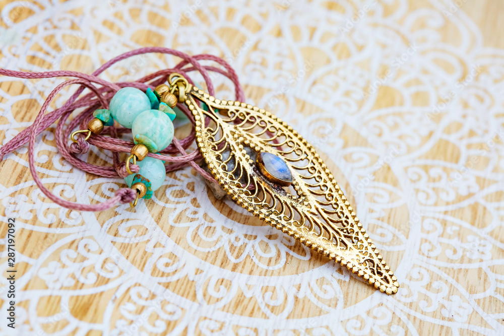 Fototapeta premium brass pendant with mineral moon stone in shape of joni on decorative background