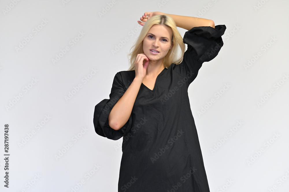 Portrait of a cute girl, a young blonde woman with beautiful curly hair in a black dress on a white background. Beauty, brightness, smile, emotions. Portrait of a cute girl, a young blonde woman with beautiful curly hair in a black dress on a white background. Beauty, brightness, smile, emotions.