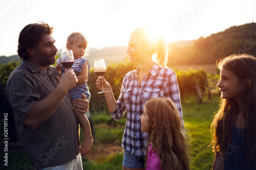 Winemaker family together in vineyard tasting vine