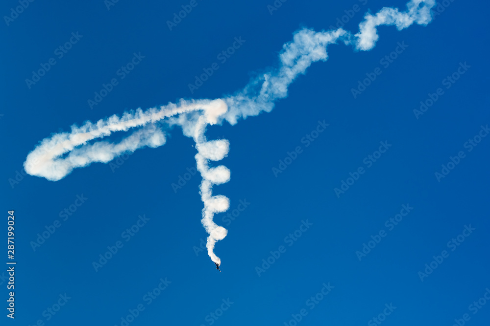 Naklejka premium An Airplane Leaving a Beautiful Spiral-Like Trail of Smoke in the Sky