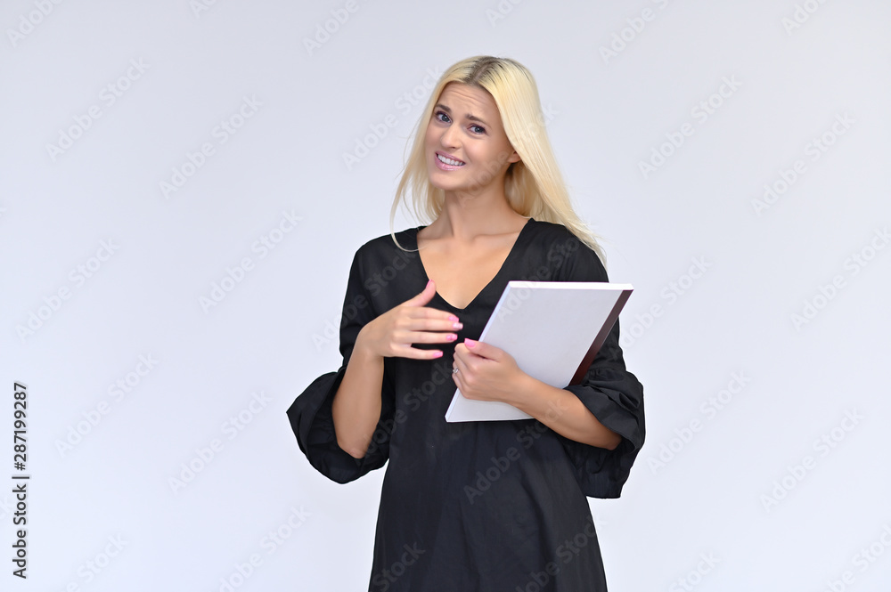 Portrait of a cute girl, a young blonde woman with beautiful curly hair in a black dress on a white background with a folder in her hands. Beauty, brightness, smile, emotions. Portrait of a cute girl, a young blonde woman with beautiful curly hair in a black dress on a white background with a folder in her hands. Beauty, brightness, smile, emotions.