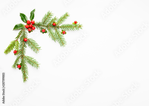 Christmas composition  with branches of spruce and holly with red berries on white background. Merry christmas greeting card with empty space for holiday text.