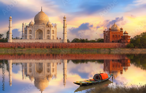 Taj Mahal Agra at sunset on the banks of river Yamuna with moody sunset sky and view of wooden boat used for tourist ride on the river  photo