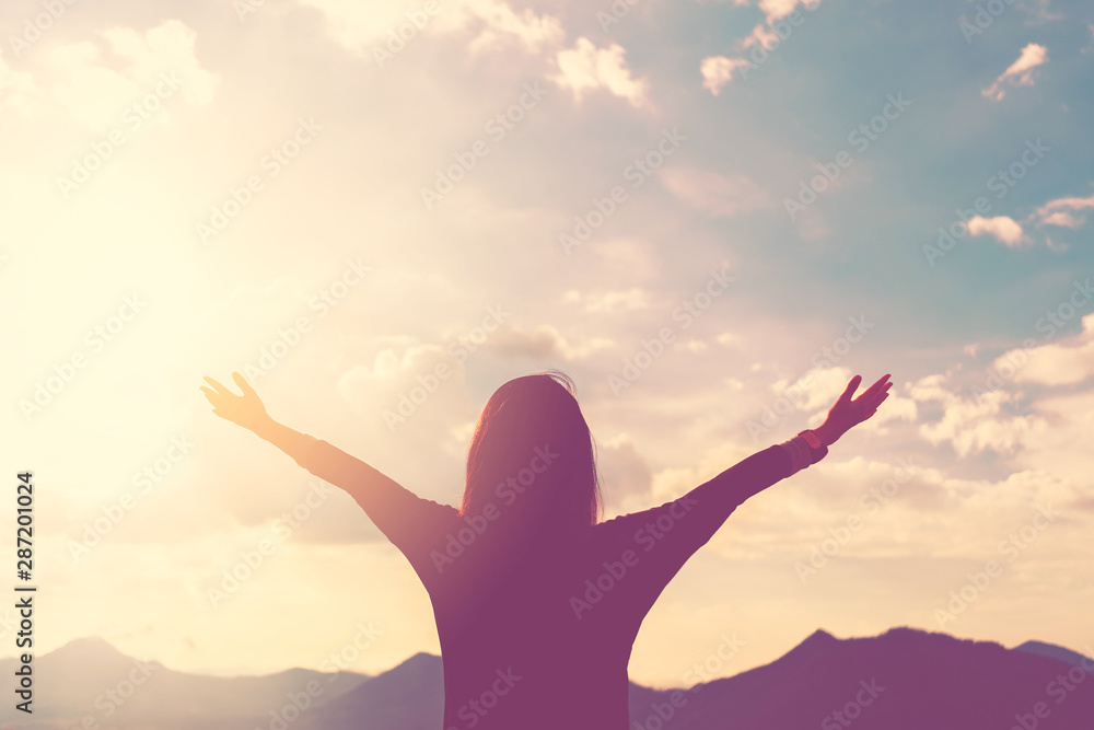 Copy space of woman rise hand up on top of mountain and sunset sky abstract background. - obrazy, fototapety, plakaty 