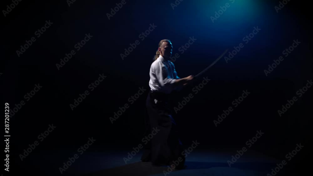 Aikido Master technique demonstration with japanese sword katana on blue smoke background. Aikido Master technique demonstration with japanese sword katana on blue smoke background.