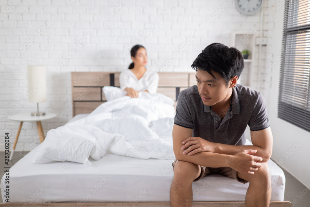couple,they have problems with quarrel. man sitting in bed he is stressed